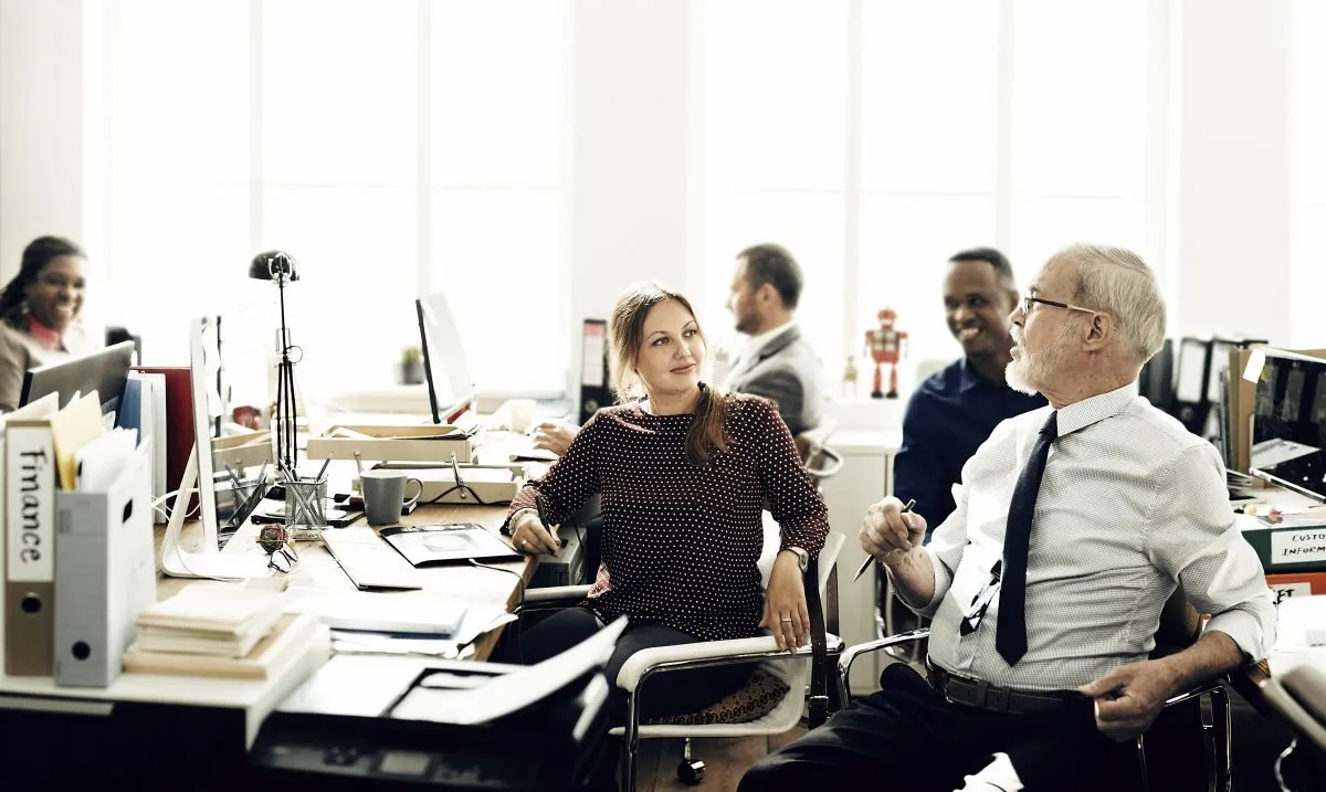 Colleagues chatting and laughing in a bright open-plan office