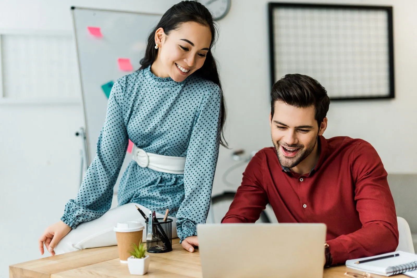 Two colleagues smiling while working through something on a laptop