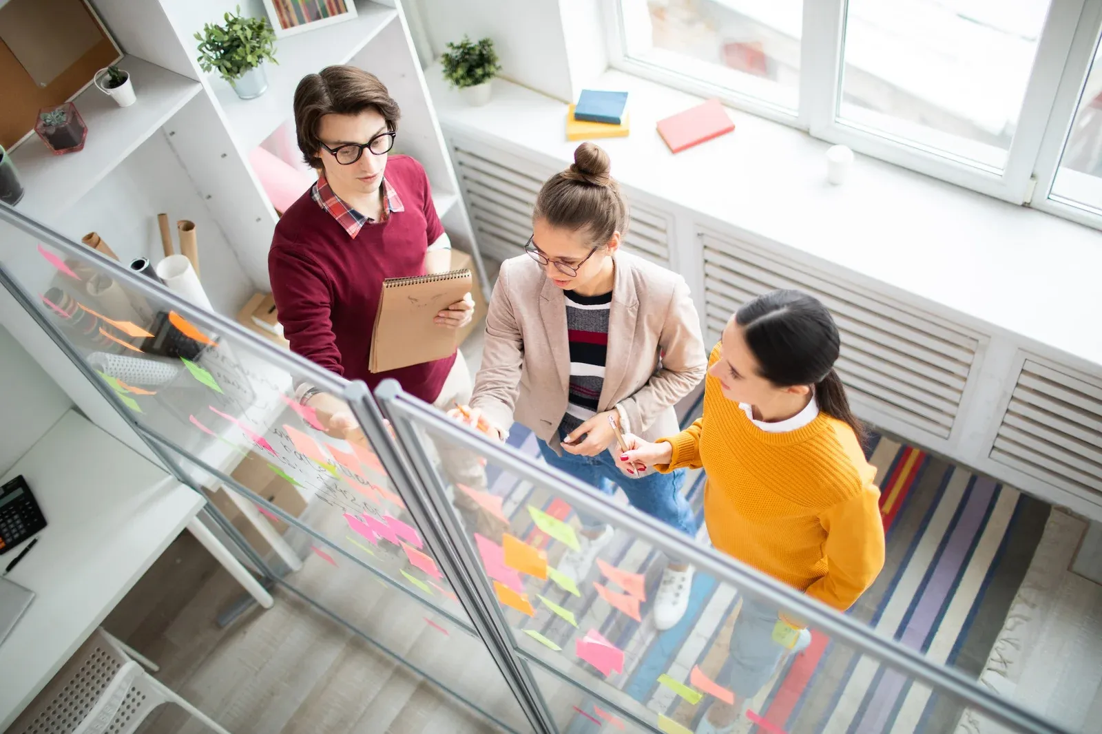 Overhead view of a team planning work at a desk covered in sticky notes