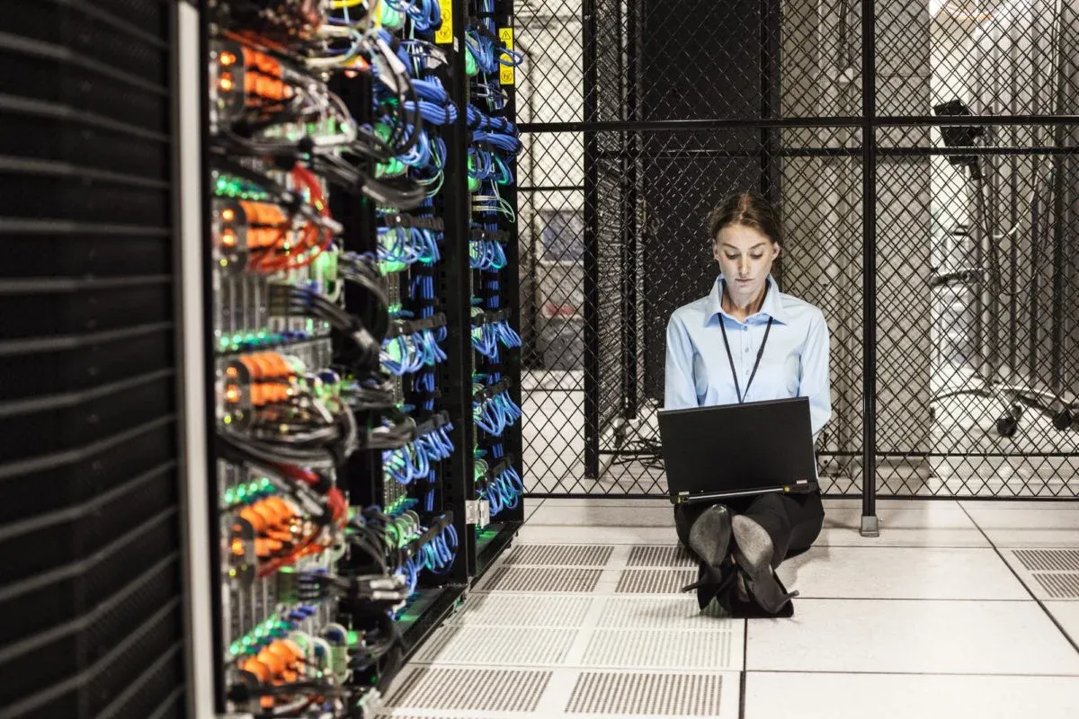 Engineer working on a laptop on the floor of a server room
