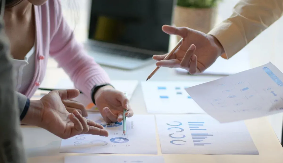 Hands reviewing printed financial charts