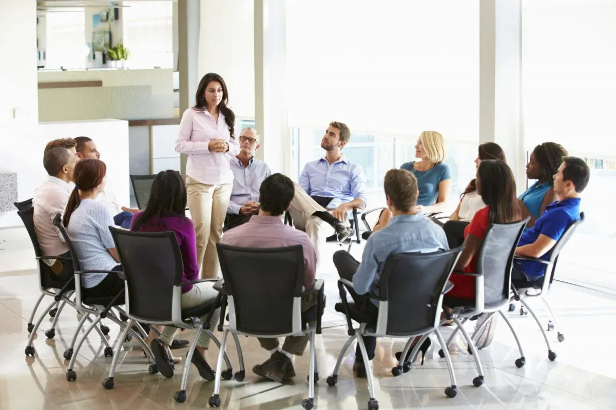 Trainer leading a group session with colleagues seated in a circle