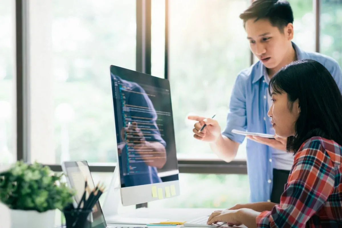 Two colleagues reviewing work together at a desktop computer