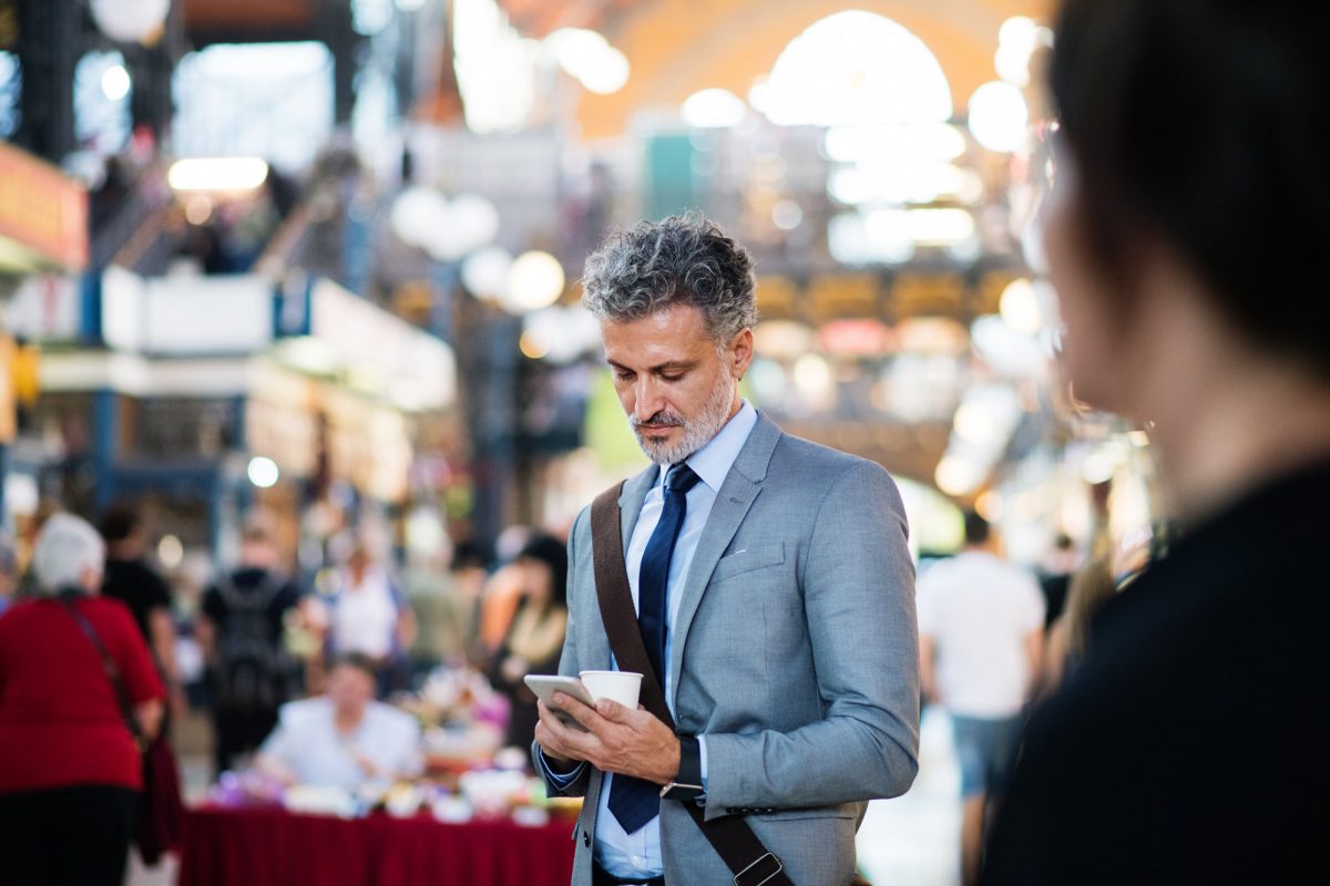 Mature businessman with smartphone in a city.