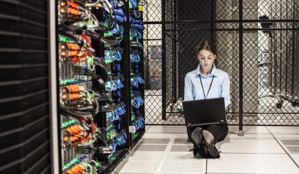 Caucasian woman technician working on computer servers in a server farm.