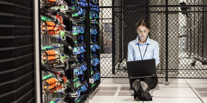 Caucasian woman technician working on computer servers in a server farm.