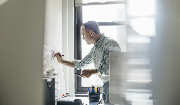 Office life. A man standing up working and making notes on a wall chart. Project management.