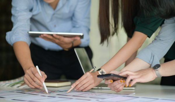 The UX team is designing an application for smartphones with a laptop in a modern office.