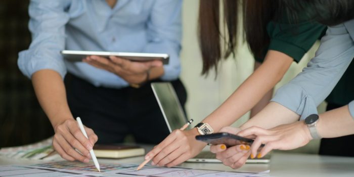 The UX team is designing an application for smartphones with a laptop in a modern office.